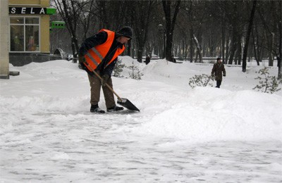 Работник коммунальной службы чистете снег возле Полтавской обласной библиотеки