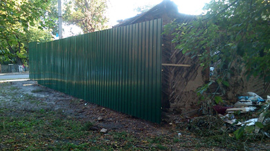 Напівзруйнований будинок, де офіційно проживають люди, обнесли новим парканом