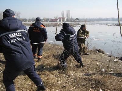 Работники МЧС на лодке зачалили тросами большие стволы поваленных деревьев и оттянули их к берегу