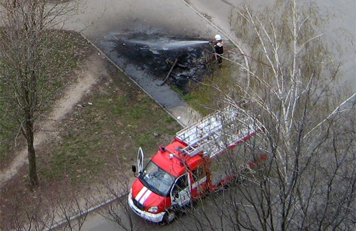 Пожарник тушит загоревшуюся кучу листьев