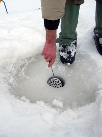 Товщину замерзання рибак Микола виміряє рукою і домашньою шумовкою.