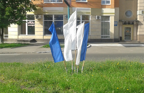 Білі та сині прапори біля палацу дозвілля «Листопад»