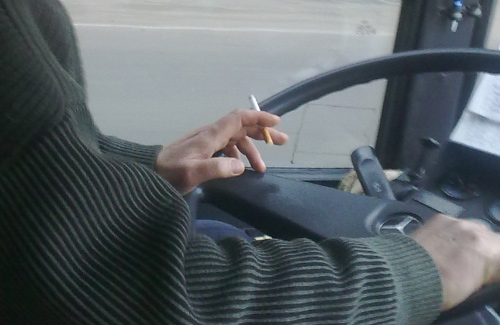 Водій автобусу за кермом з цигаркою