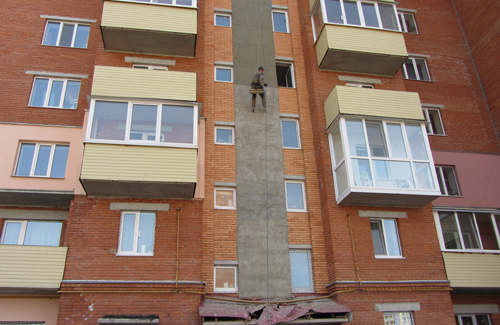 На Гожулянській, 26 на фасаді демонтують цеглу і штукатурять стіну