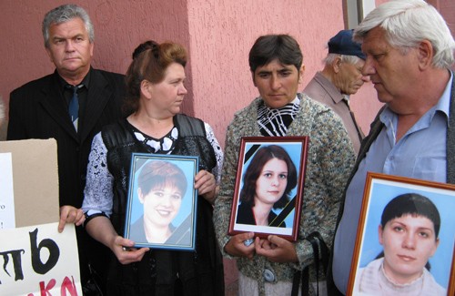 Родители держат фото убитых дочерей