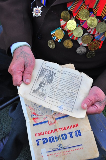 Ветеран, учасник Великої Вітчіизняної війни П.К. Соловей демонструє свої грамотиза бойові заслуги
