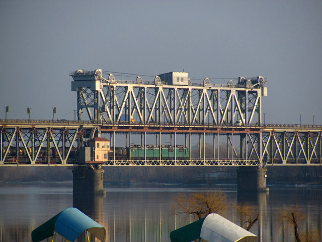 Тягач товарного поезда проходит подъемную часть моста