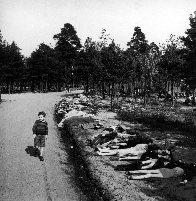 Немецкий мальчик идет по дороге мимо сотен тел погибших заключенных концлагеря Берген-Бельзен