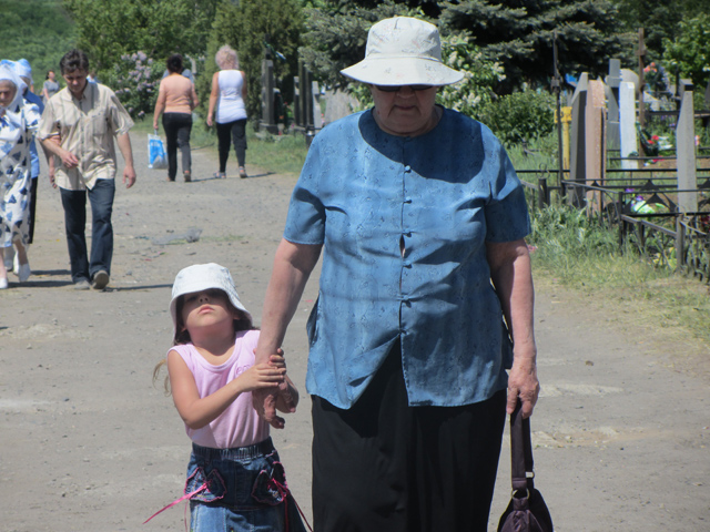 Бабуся з онукою йдуть із кладовища
