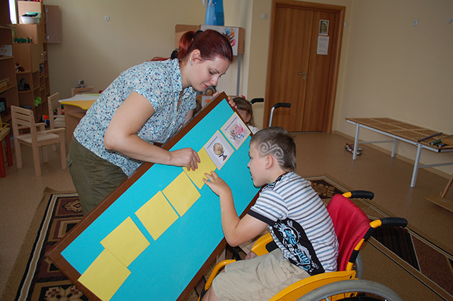 Учитель-реабилитолог Виктория Соловьева показывает ребенку распорядок дня в картинках