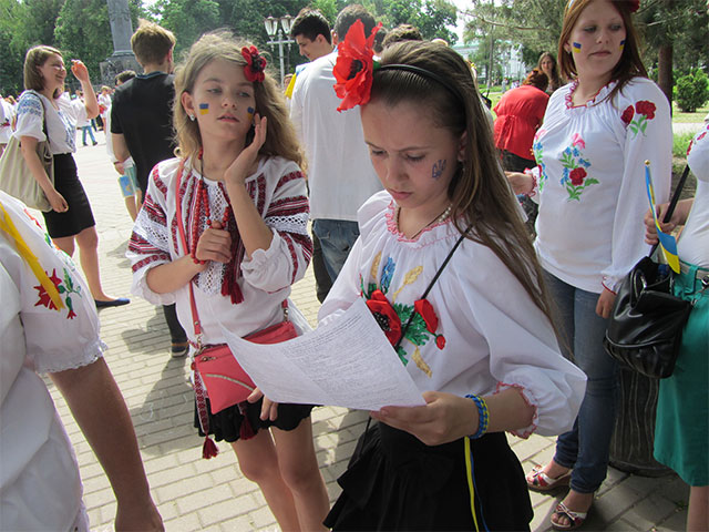 Учасниця маршу поспішає вивчити слова української пісні, щоб заспівати йдучи до Білої альтанки 
