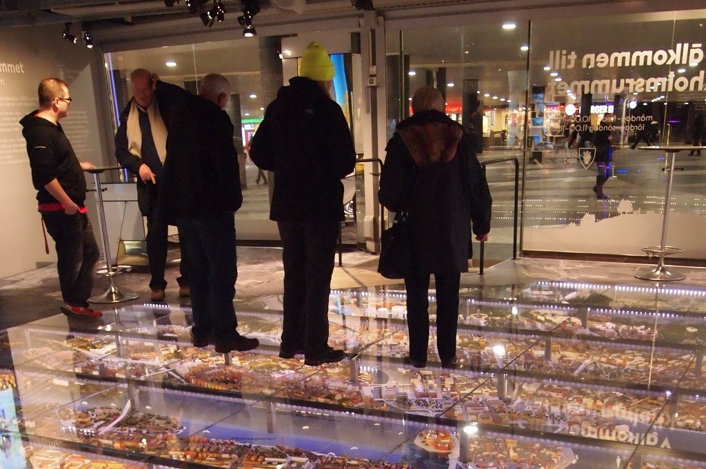 Кімната нового Cтокгольму — люди ходять по величезному макету міста, зверху над яким товсте скло