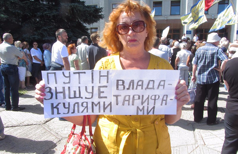 Жінка з плакатом «Путін вбиває нас кулями, а влада — тарифами»