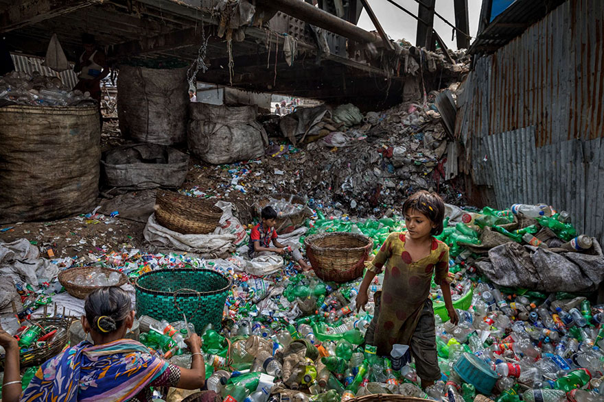 Під мостом на річці Буріганга в Бангладеш родина знімає етикетки з пластикових пляшок, сортуючи зелені і прозорі, щоб продати скупникові. Фото: Randy Olson/National Geographic (Джерело - Новое время)