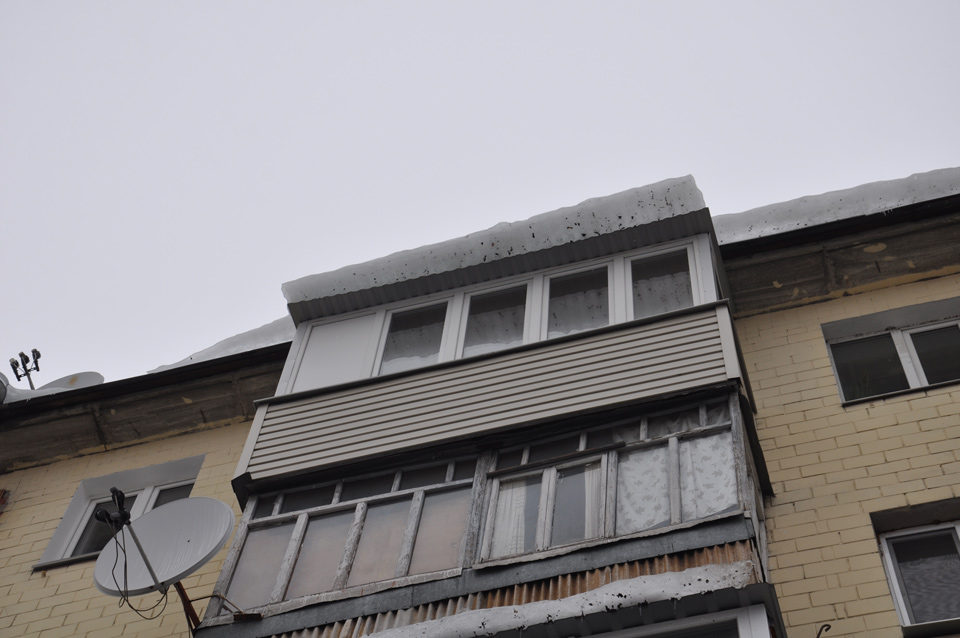 Поряд балкон з даху якого звисає ще одна брила