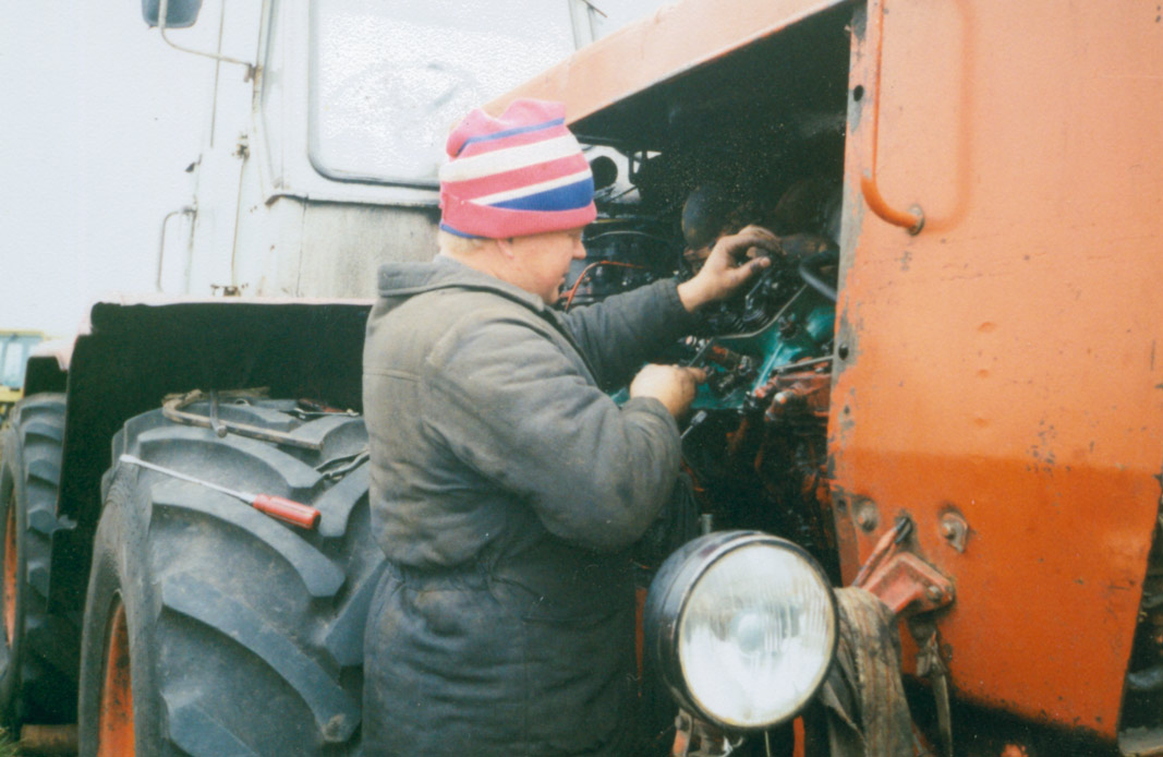 Олександр Подоляка ремонтує трактор Т-150 середина 90-х років