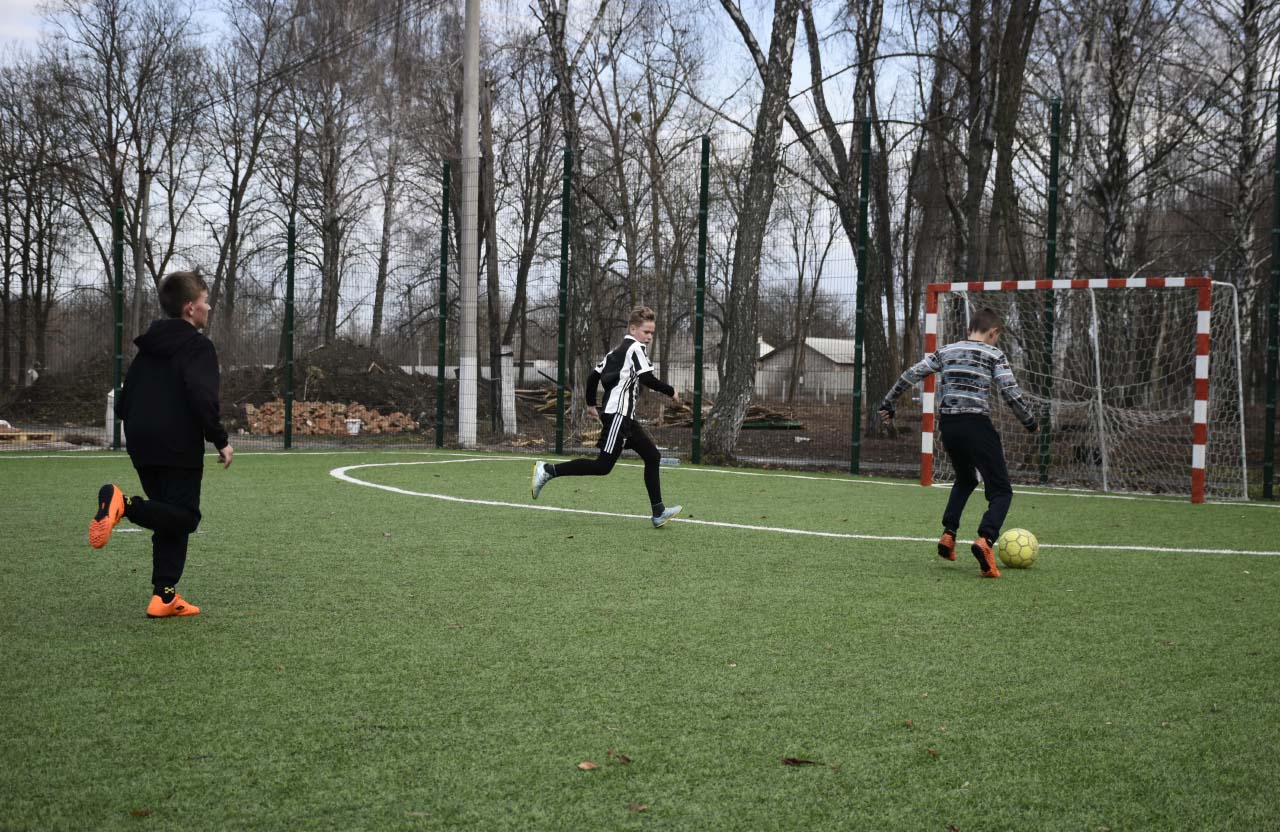 Дітлахи грають у футбол на новому полі зі штучним покриттям